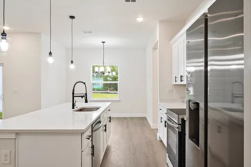 Kitchen with white cabinets, pendant lights and a steel fridge